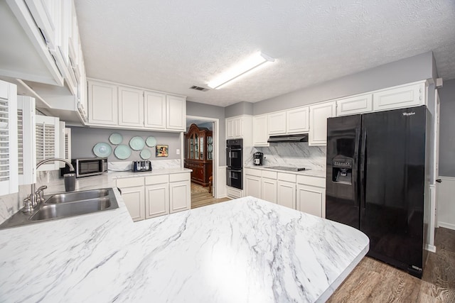 6909 Trapper Way, Midland, GA 31820 - kitchen featuring black appliances, wood finished floors, a peninsula, white cabinetry, and a textured ceiling