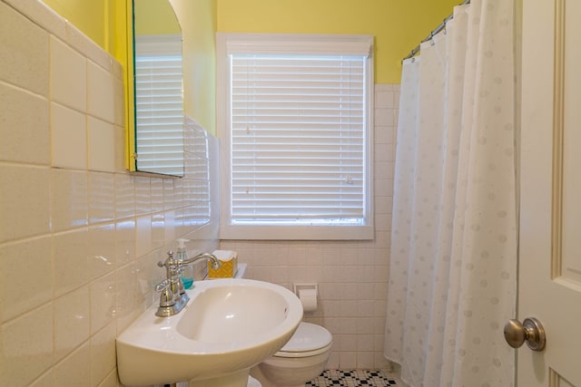 full bathroom with a shower with shower curtain, a sink, tile walls, and toilet