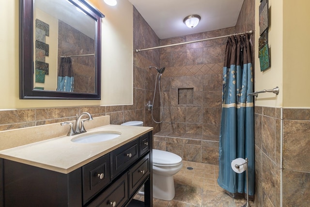 bathroom featuring tiled shower, toilet, tile walls, and vanity