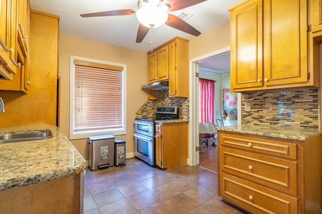 kitchen with ceiling fan, under cabinet range hood, a sink, backsplash, and double oven range