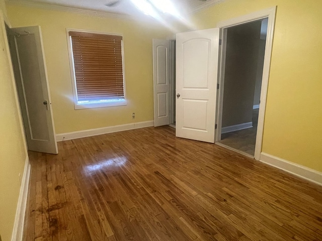 unfurnished bedroom featuring crown molding, wood finished floors, and baseboards