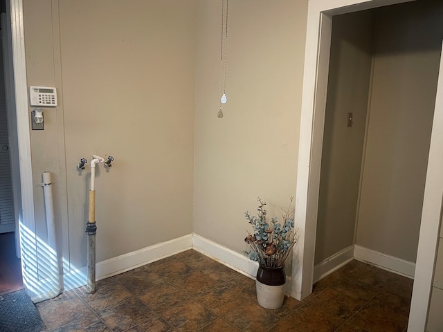 laundry room with stone finish floor and baseboards