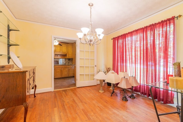 dining space featuring light wood-style floors, baseboards, ornamental molding, and a notable chandelier