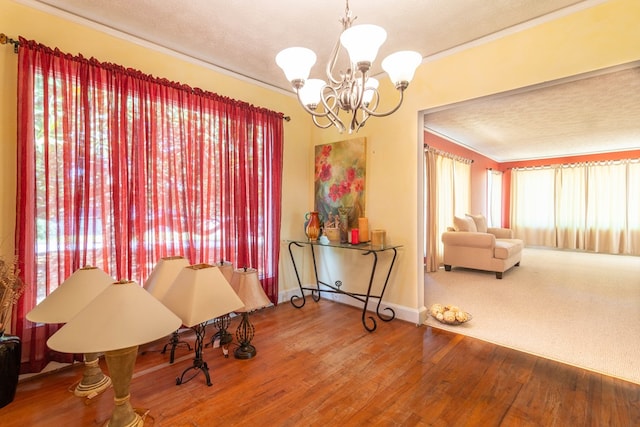 sitting room with ornamental molding, a textured ceiling, wood finished floors, a chandelier, and baseboards