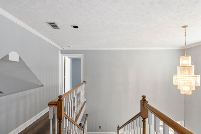 stairs with hardwood / wood-style flooring, crown molding, a textured ceiling, and an inviting chandelier