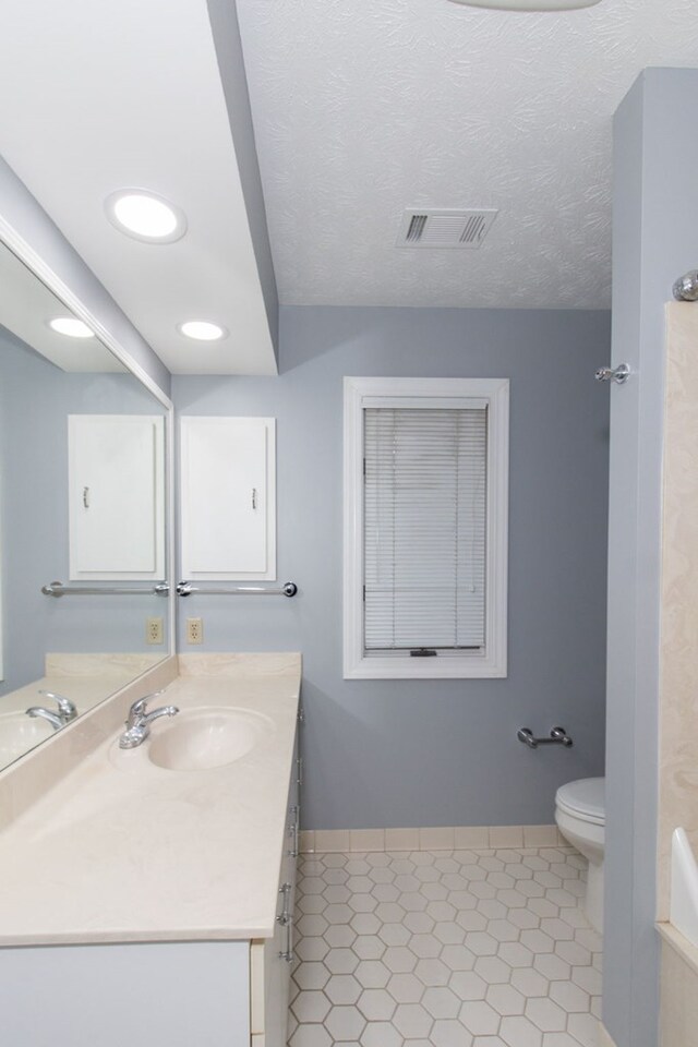 bathroom with vanity, toilet, and a textured ceiling