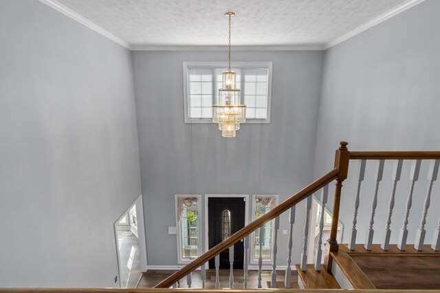 stairway featuring a textured ceiling, a notable chandelier, and crown molding