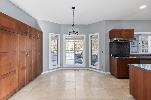 kitchen featuring stainless steel dishwasher, gas stovetop, decorative light fixtures, a notable chandelier, and dark stone countertops