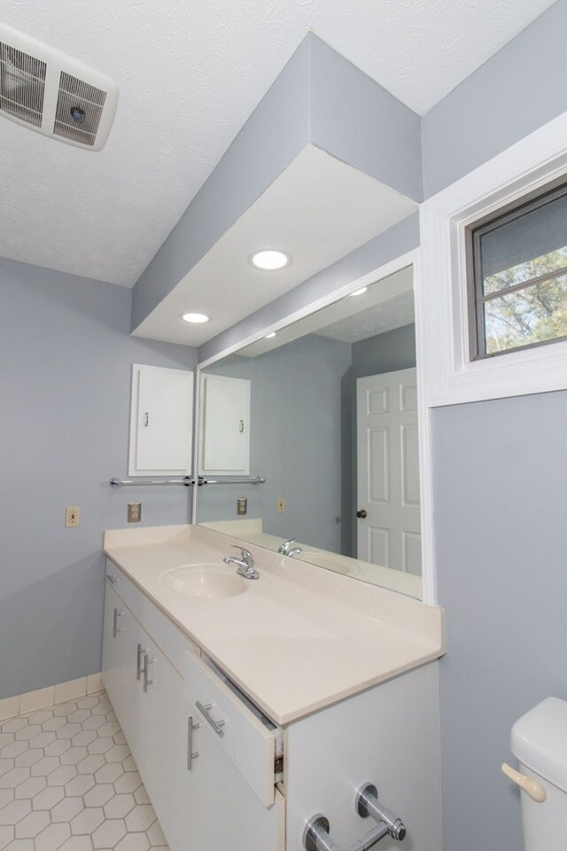 bathroom with tile patterned flooring, vanity, a textured ceiling, and toilet