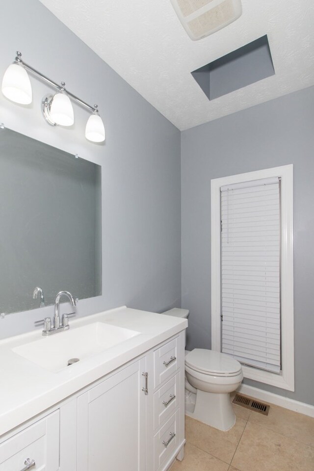 bathroom featuring tile patterned floors, vanity, a textured ceiling, and toilet