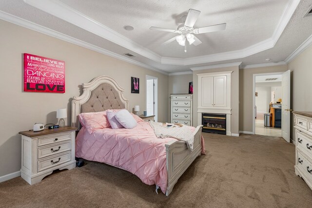 485 Boyd Branch Dr, Upatoi, GA 31829 - bedroom with light colored carpet, a tray ceiling, ornamental molding, a glass covered fireplace, and baseboards