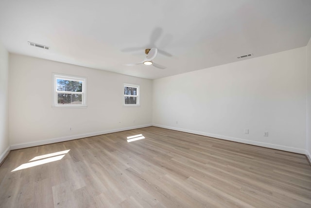 empty room featuring light wood-style flooring, visible vents, and baseboards