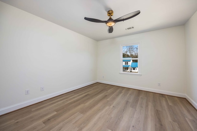 empty room with ceiling fan, wood finished floors, visible vents, and baseboards