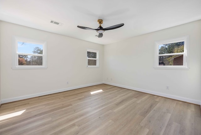 empty room featuring a wealth of natural light, light wood-style flooring, and visible vents