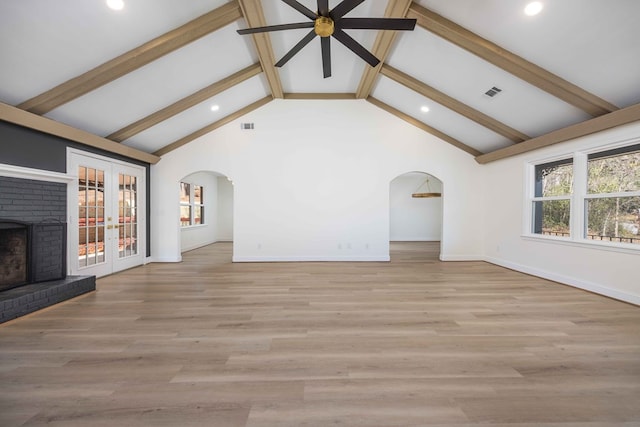 unfurnished living room featuring visible vents, arched walkways, beamed ceiling, wood finished floors, and a brick fireplace