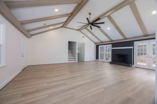 unfurnished living room with vaulted ceiling with beams, french doors, a fireplace, and light wood-style floors