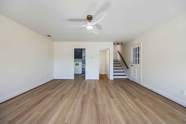 empty room with light wood-style flooring, stairs, baseboards, and a ceiling fan