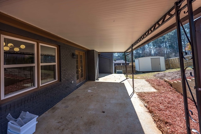 view of patio / terrace with an outdoor structure, fence, and a shed