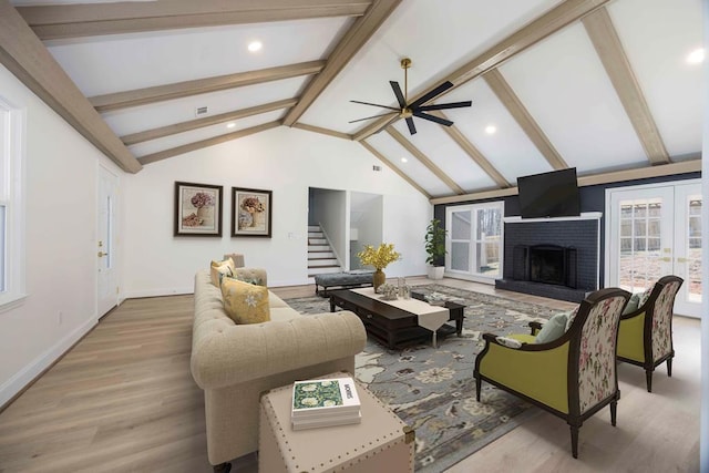 living room with vaulted ceiling with beams, wood finished floors, baseboards, stairs, and a brick fireplace