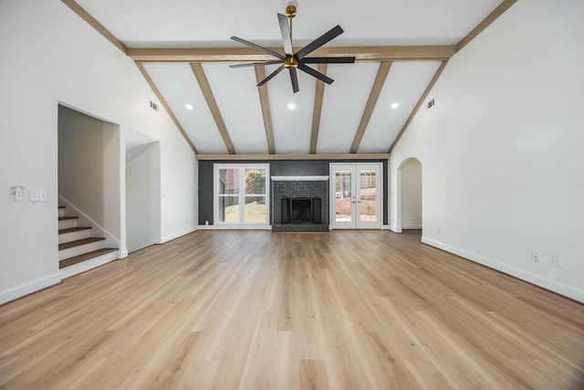 unfurnished living room with light wood finished floors, a fireplace, baseboards, and beamed ceiling