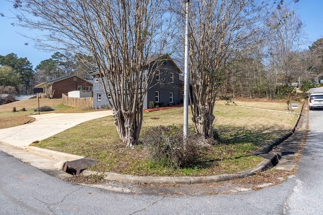 view of front of home featuring driveway, a front lawn, and fence