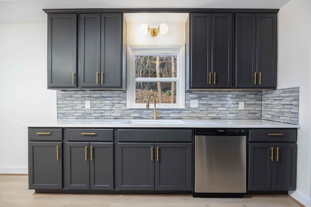 kitchen with light countertops, light wood-style flooring, decorative backsplash, a sink, and dishwasher