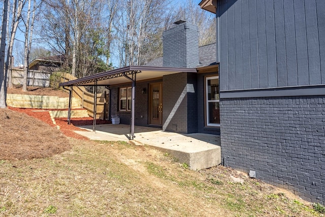 rear view of property with a patio, brick siding, and a chimney