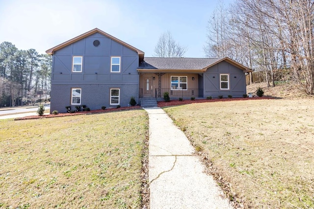 split level home featuring covered porch, brick siding, and a front yard