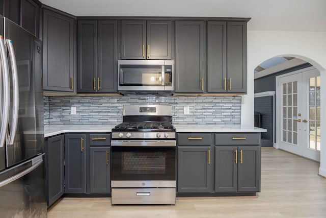 kitchen featuring french doors, light countertops, backsplash, appliances with stainless steel finishes, and light wood-type flooring