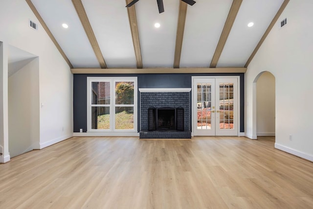 unfurnished living room with lofted ceiling with beams, a fireplace, wood finished floors, and baseboards