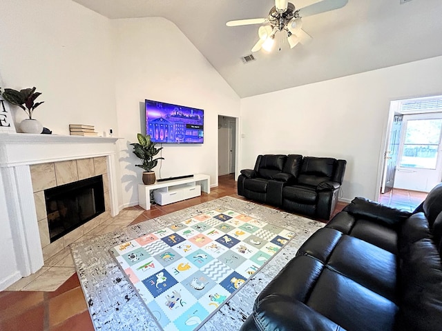 living room featuring tile patterned floors, ceiling fan, a tile fireplace, and vaulted ceiling