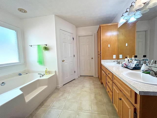 bathroom with tile patterned floors, a washtub, vanity, and a textured ceiling