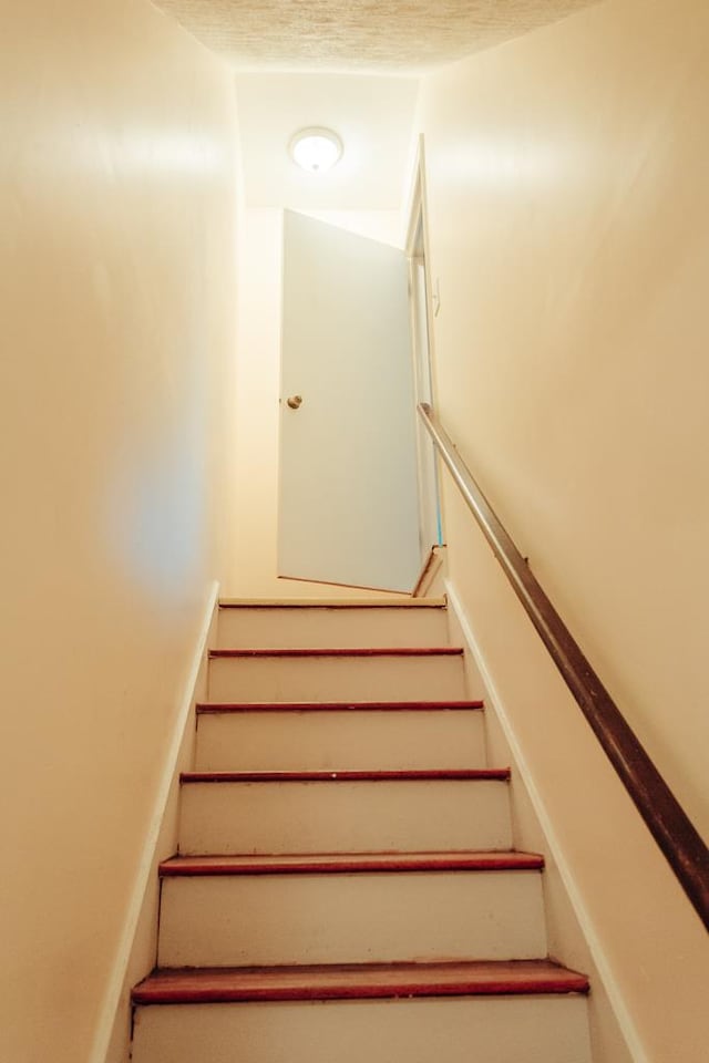 stairs featuring a textured ceiling