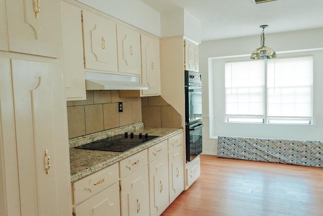 kitchen featuring pendant lighting, white cabinetry, decorative backsplash, black appliances, and light hardwood / wood-style flooring