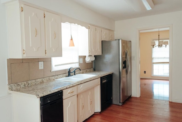 kitchen with pendant lighting, a wealth of natural light, dishwasher, sink, and hardwood / wood-style flooring