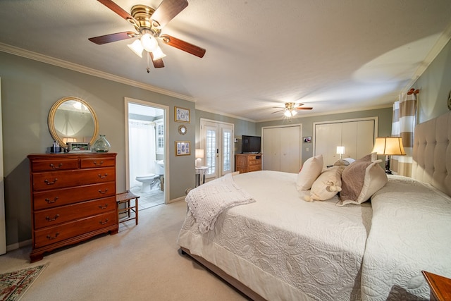 carpeted bedroom featuring ensuite bathroom, ornamental molding, ceiling fan, multiple closets, and french doors