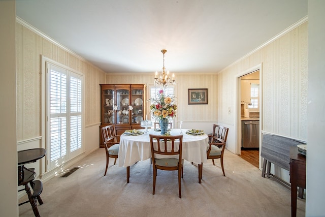 dining room with crown molding, light carpet, and a chandelier