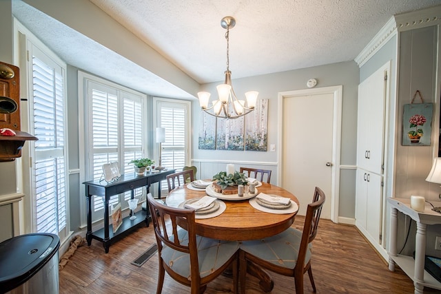 dining room featuring a notable chandelier, dark wood-type flooring, and a textured ceiling