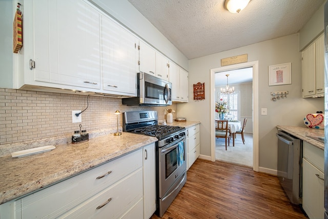 kitchen with dark wood-type flooring, white cabinetry, light stone counters, tasteful backsplash, and appliances with stainless steel finishes