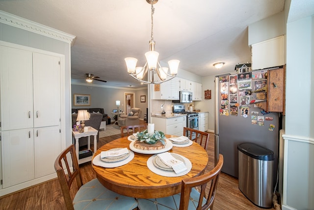 dining space with hardwood / wood-style flooring, ornamental molding, ceiling fan with notable chandelier, and a textured ceiling