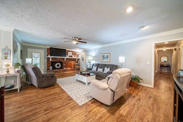 living room featuring wood-type flooring, a textured ceiling, crown molding, and a fireplace