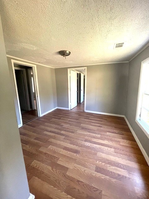 unfurnished room with a textured ceiling, dark hardwood / wood-style floors, and crown molding