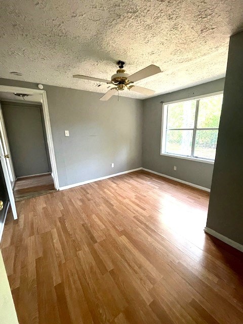 unfurnished room featuring hardwood / wood-style flooring, ceiling fan, and a textured ceiling