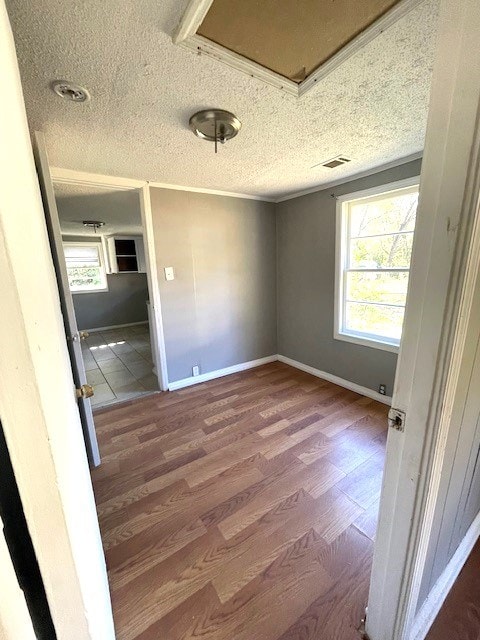 interior space with wood-type flooring, a textured ceiling, and crown molding