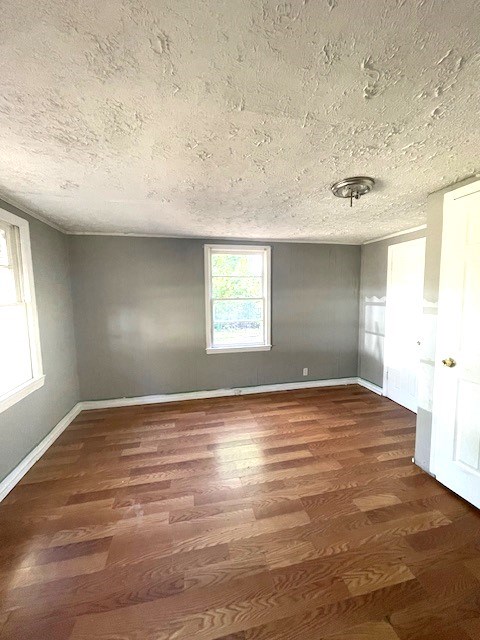 spare room featuring a textured ceiling and dark hardwood / wood-style floors