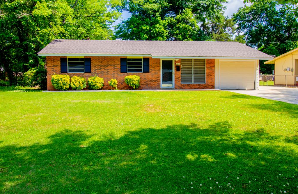 ranch-style home featuring an attached garage, brick siding, a front yard, and concrete driveway