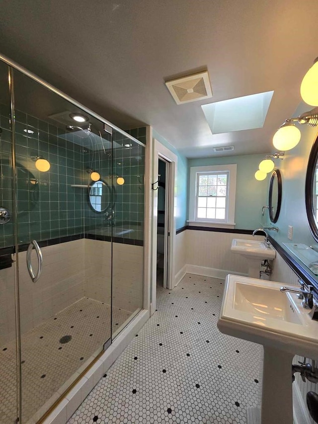 bathroom featuring sink, a skylight, and a shower with shower door