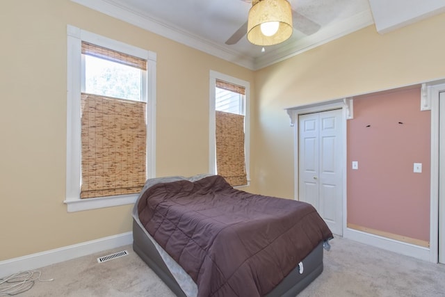 carpeted bedroom with ceiling fan, ornamental molding, and a closet