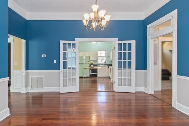 unfurnished dining area with dark hardwood / wood-style flooring, a notable chandelier, and french doors