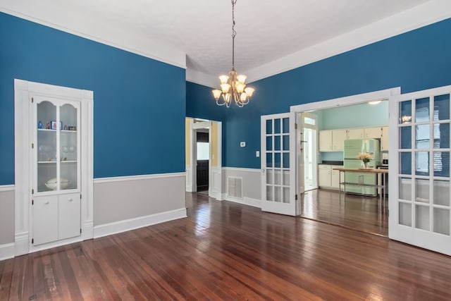 unfurnished dining area with a notable chandelier and dark hardwood / wood-style flooring